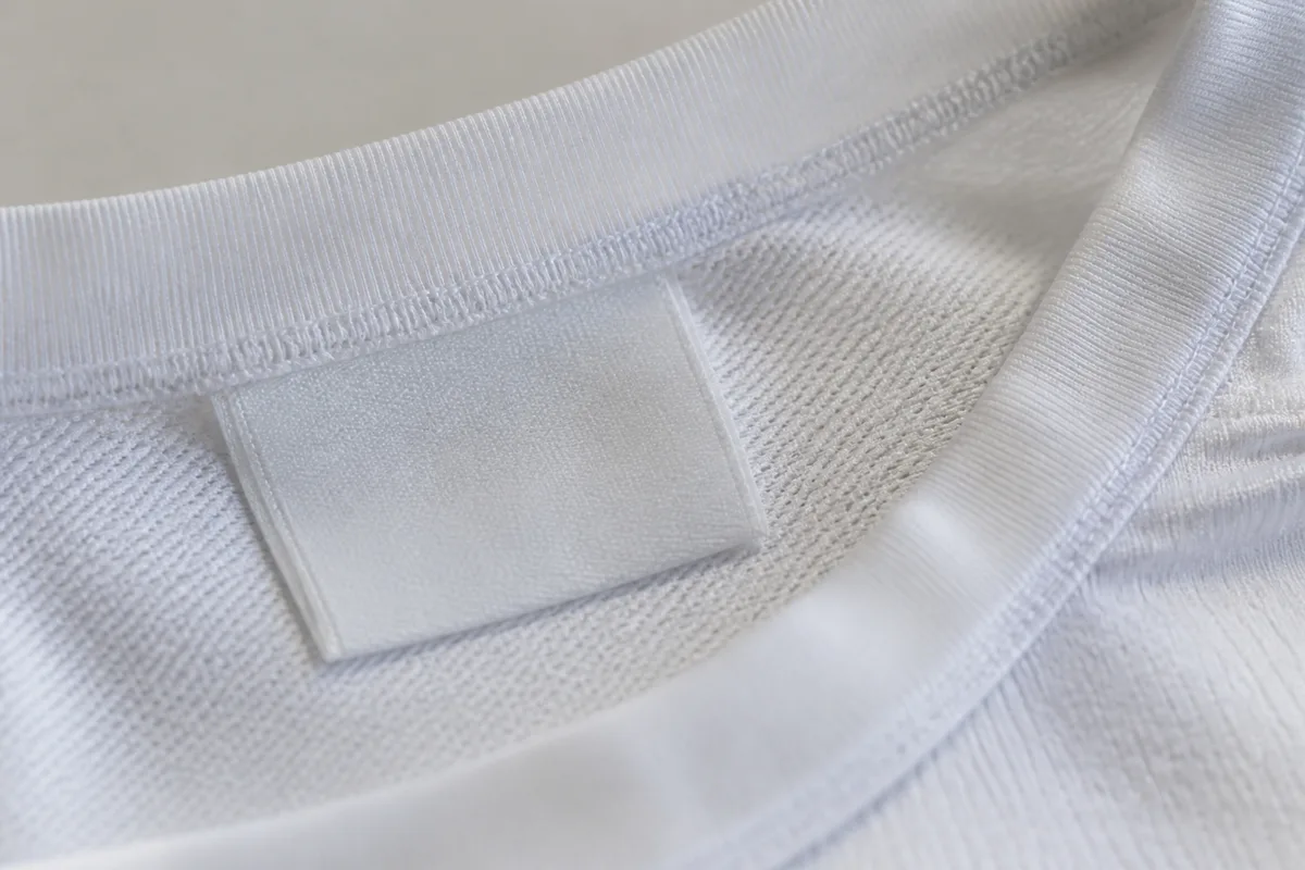 Étiquette intérieure et couture de col d&rsquo;un maillot de football blanc photographiées de très près