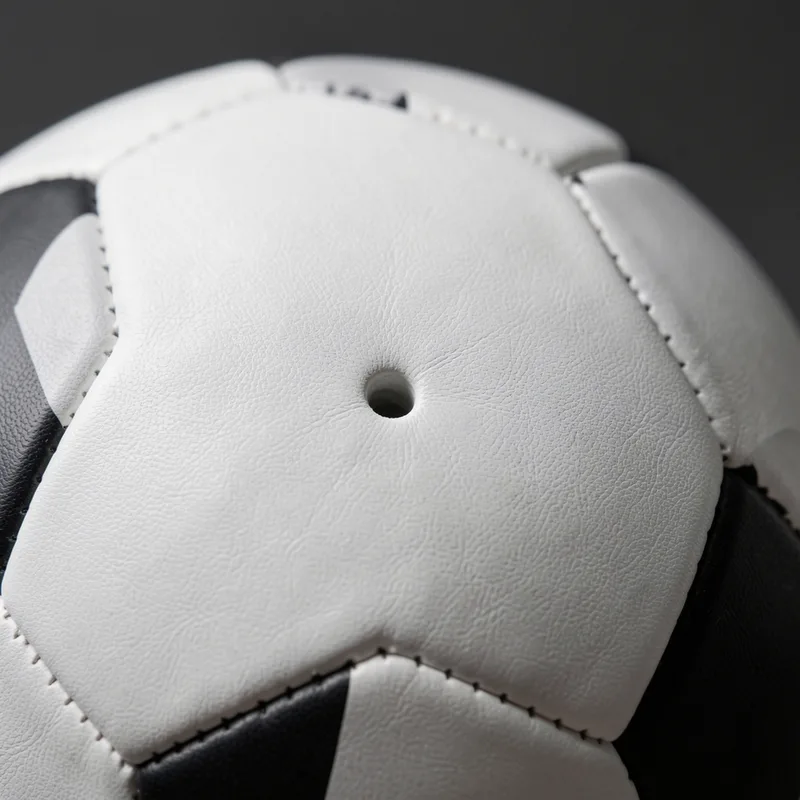 Détail rapproché des coutures et de la valve d’un ballon de football blanc et noir